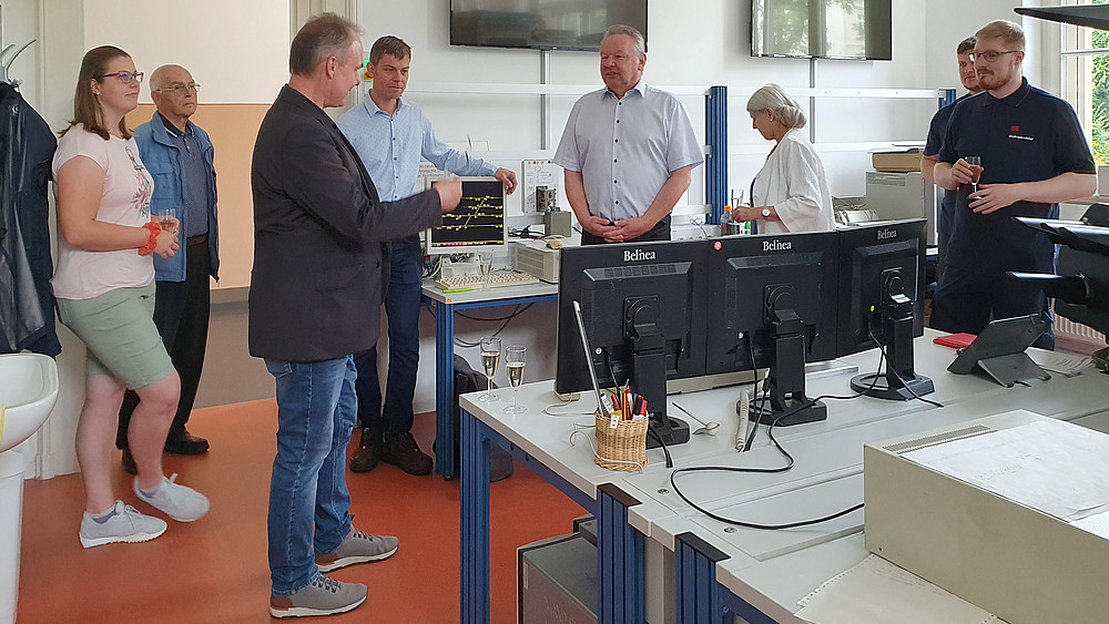 The Dean of Studies in Electrical Engineering, Prof. Müller, in conversation with the owner of BCG, Mr. Torsten Ratke, in a room full of screens and electronic devices.