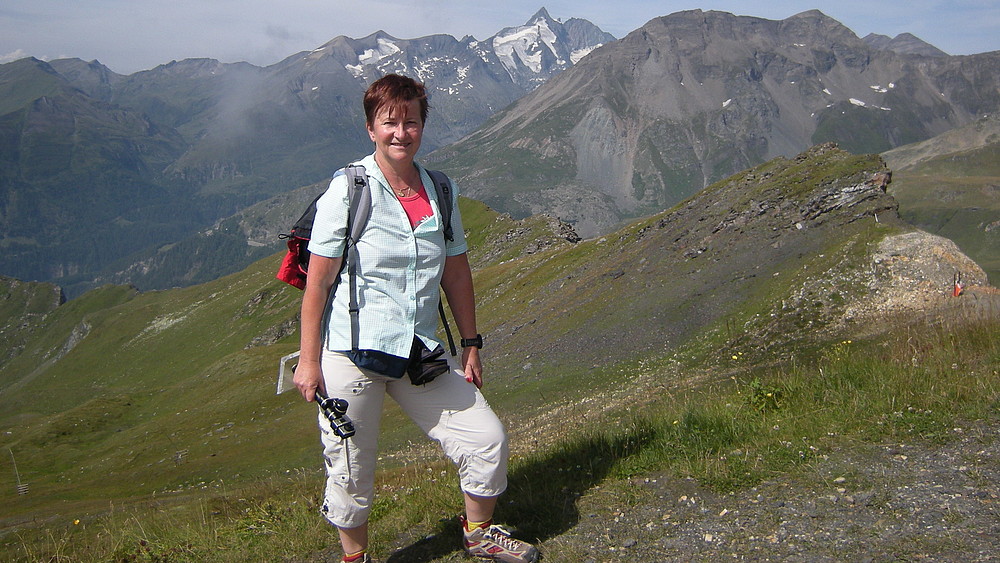 Prof. Spangenberg in a meadow. High mountains can be seen in the background.