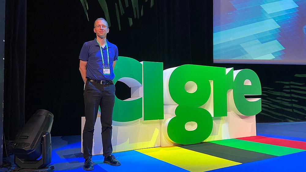 Stefan Kornhuber in front of the cigre display in a presentation hall.