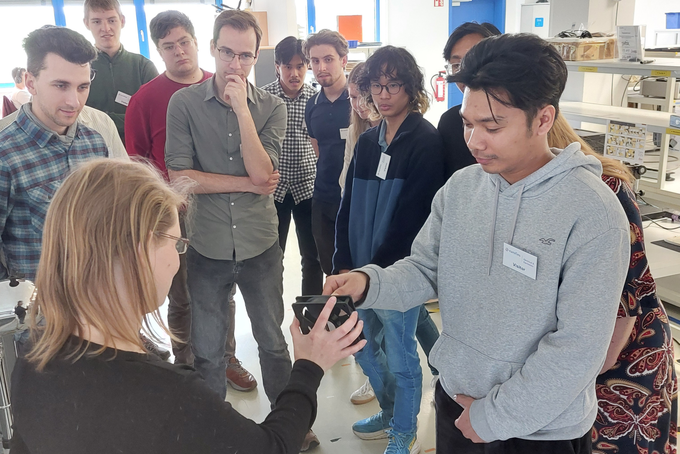 Mehrere Personen stehen im Halbkreis und bekommen von einer Frau im Vordergrund etwas gezeigt